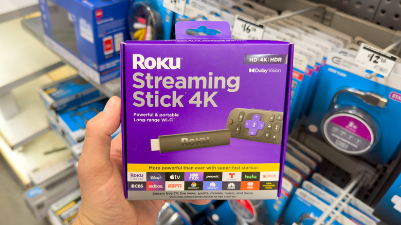 Roku Streaming Stick 4K retail box held in an electronics store aisle.