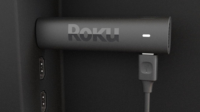 Roku Streaming Stick plugged into a TV with a power cable connected.