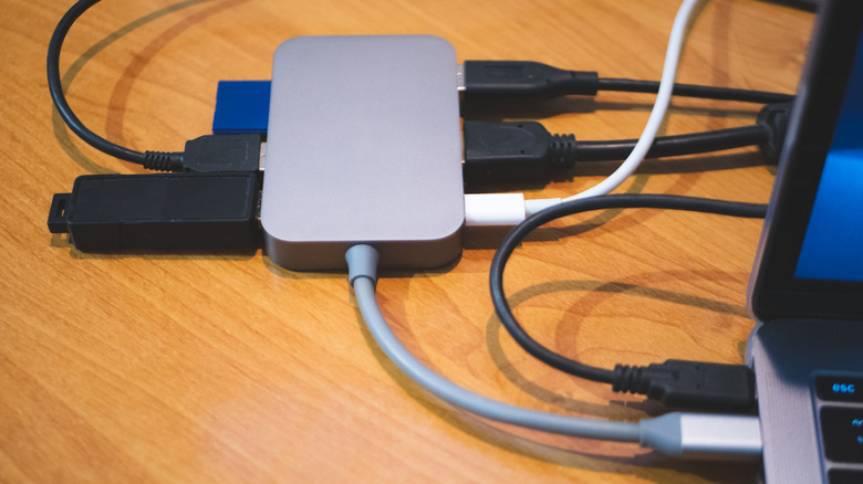 Close-up of a USB hub with multiple plugged in devices and connected to a laptop