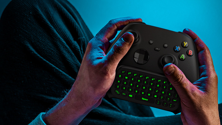 hand holding a Moko green backlight keyboard connected to an Xbox controller
