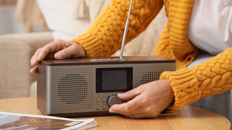 An elderly person using a classic radio receiver