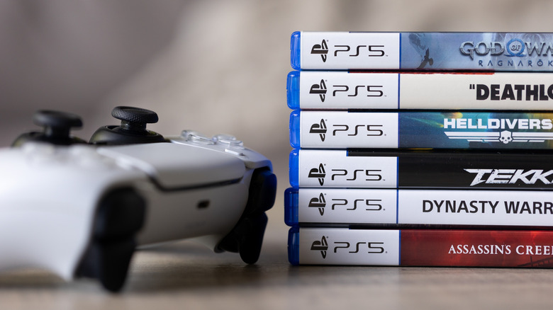 PS5 game cases stacked beside a DualSense controller.