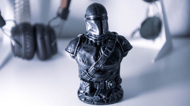 3D-printed Mandalorian bust figurine on a desk.
