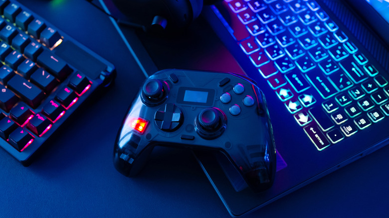 Gaming controller beside an RGB keyboard and laptop.