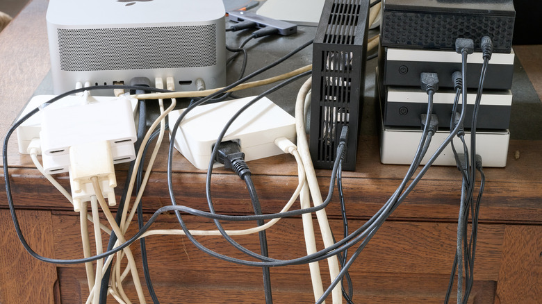 Cluttered devices and cables on a desk.