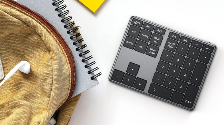 The iClever Bluetooth Number Pad sitting next to a brown backpack