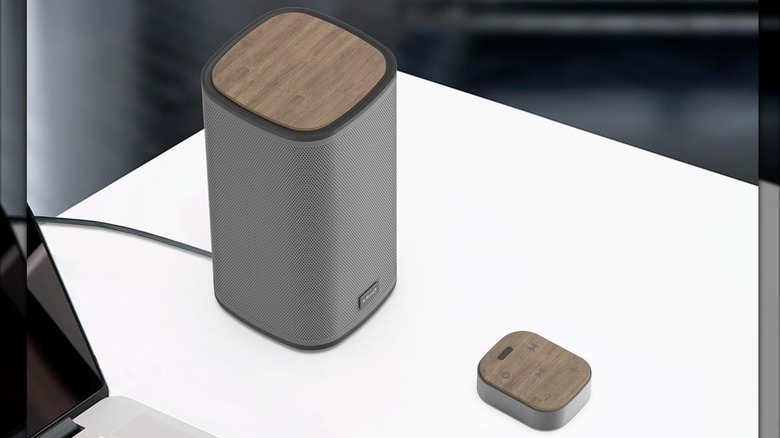 The KEiiD Bluetooth Speakers sitting on a TV stand in between a monitor, keyboard, and mouse