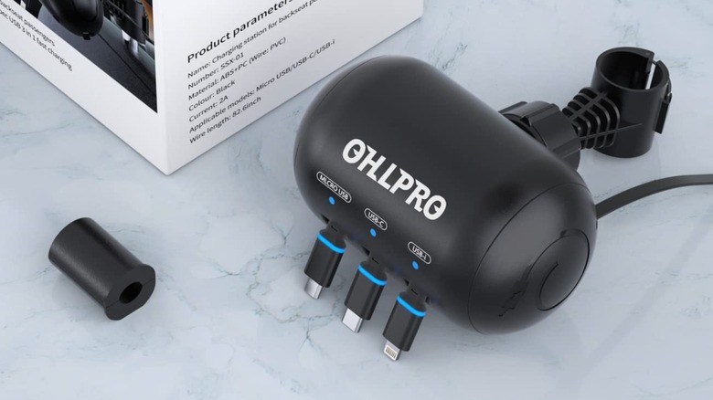 The Ohlrpo 3-in-1 Retractable Backseat Car Charging Station sitting on a counter next to its box along with a foam tube for keeping the unit in place when attached to a headrest