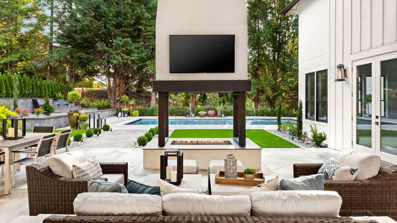 A TV mounted above a fire pit in a backyard patio