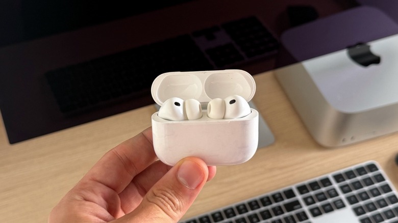 AirPods Pro 3 on its charging case with a Mac Studio and Studio Display behind it