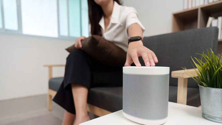 A woman activates a smart speaker on a table.