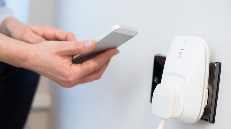 A person controlling a smart plug with a smartphone.