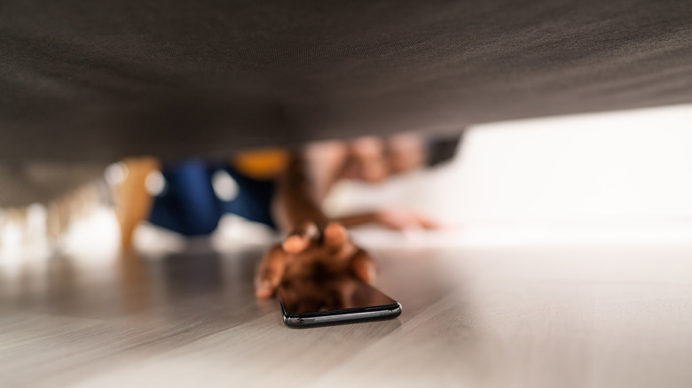 Person reaching for phone under the couch