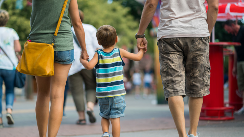 Little kid walking with parents in public