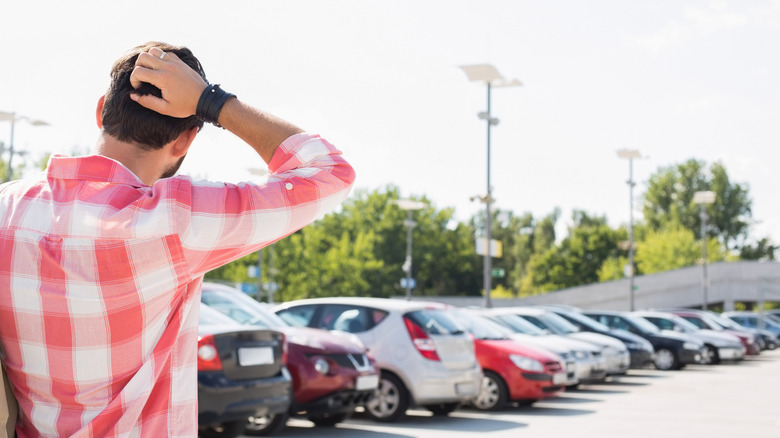 Person scratching his head while finding car in parking lot