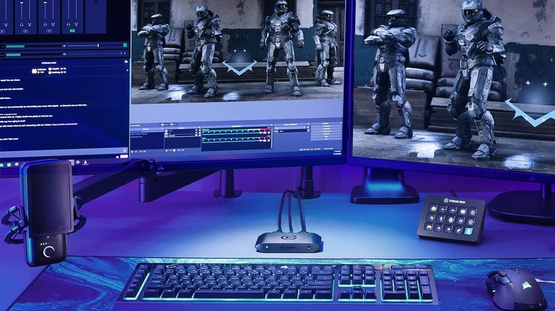 An Elgato capture card beneath computer monitors.