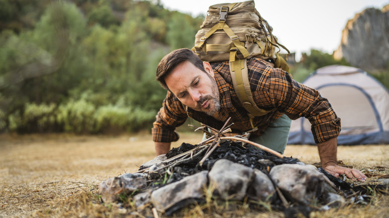 A man building a fire at a campsite