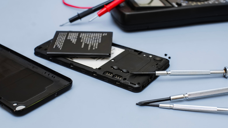 A battery extracted from a smartphone using tools