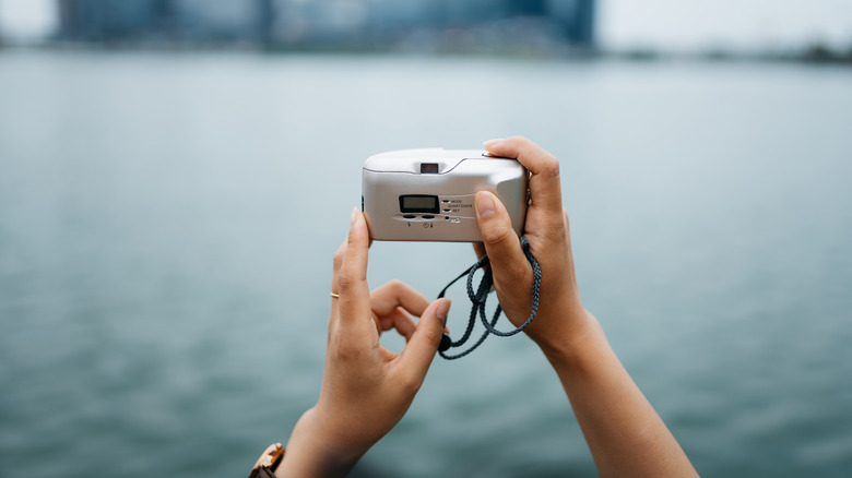 Holding a point and shoot camera for a photo of the water