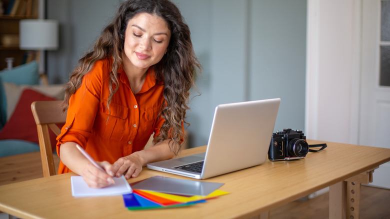 A woman prepares for crafting with supplies and a camera on her desk