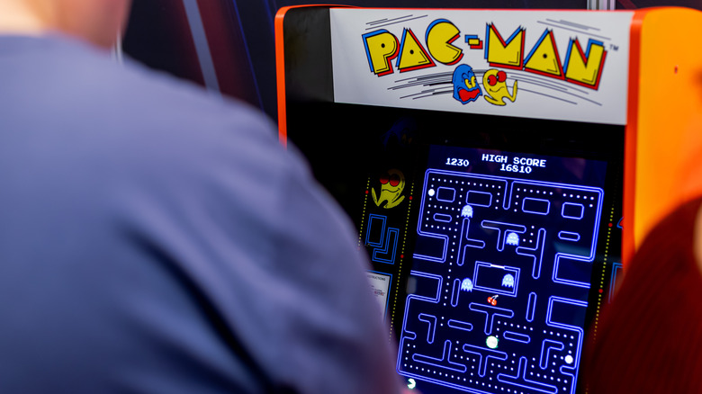 Man playing Pac Man arcade game