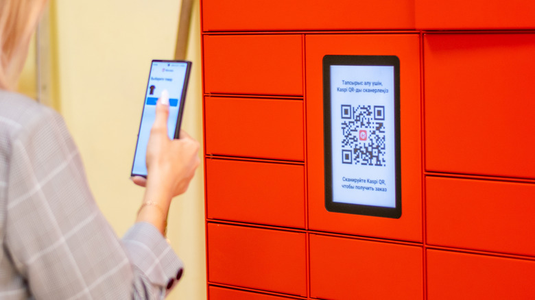 Woman scanning QR code displayed on screen on the wall