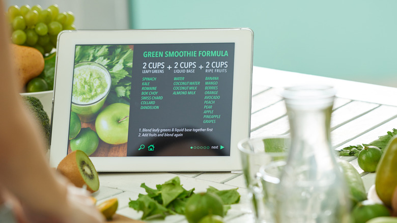 Screen displaying recipe for green smoothie with green veggies and fruits around