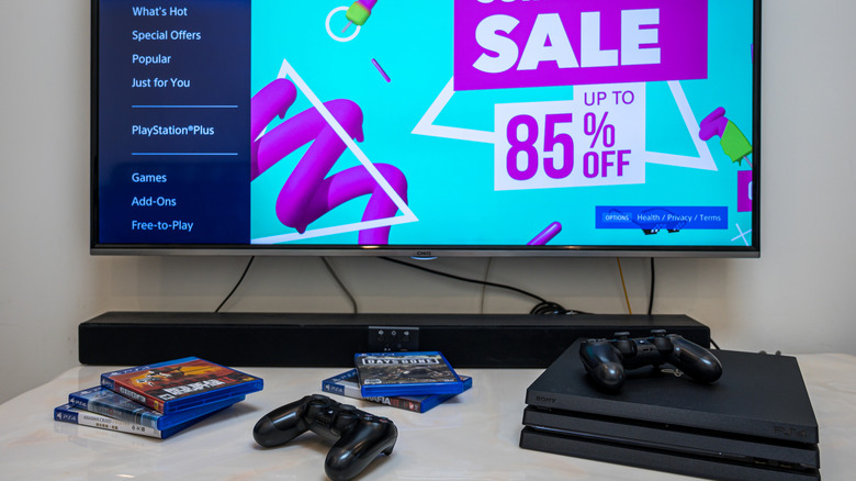 A PS4 Pro, 2 controllers, and several games, resting on a table in front of a screen