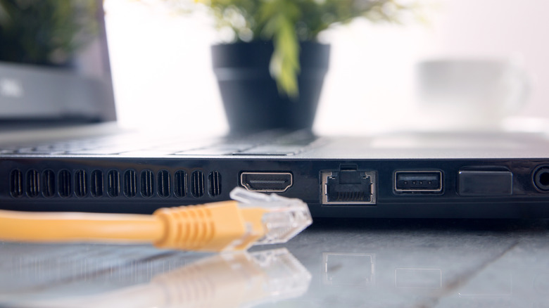 ethernet cable placed next to a laptop on a shiny platform