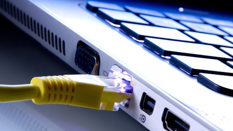 yellow ethernet cable connected to a laptop with HDMI and other ports visible