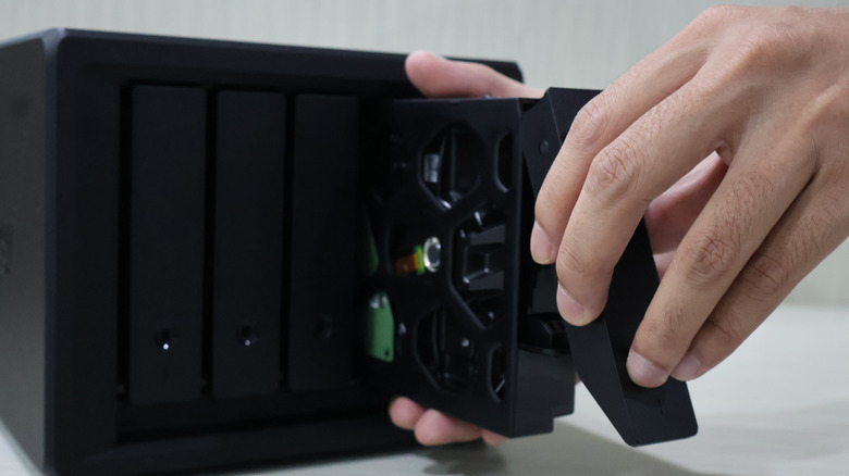 person inserting a hard drive into a network attached storage