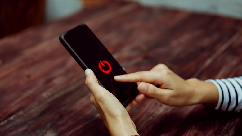 Person tapping a power off icon on their phone screen