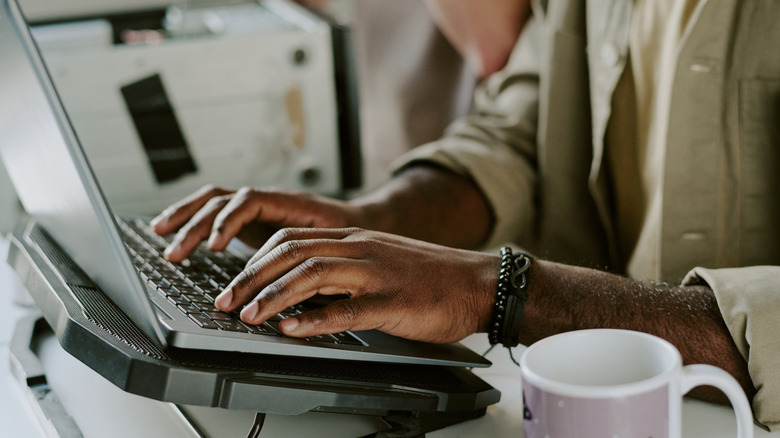 A person using a laptop with a cooling pad