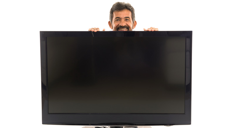 A man hiding behind a TV screen.