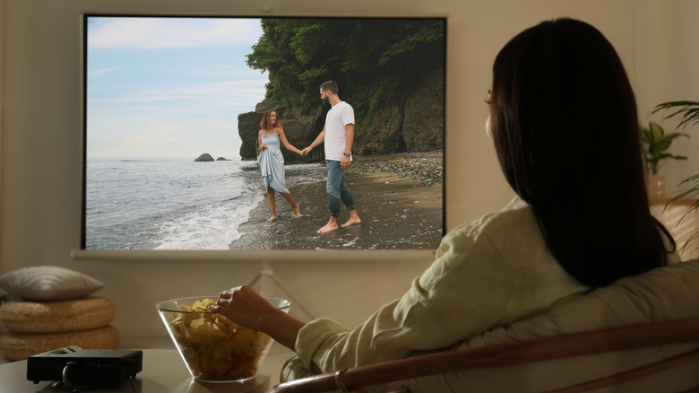 A woman watching a movie on a projector.