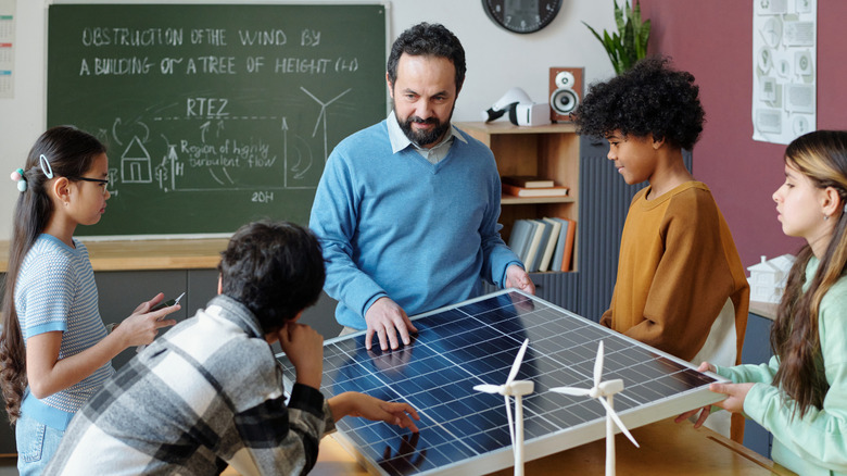 A teacher uses a solar panel to explain solar power to his students.