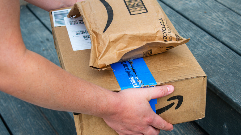 A person holding a stack of Amazon deliveries.
