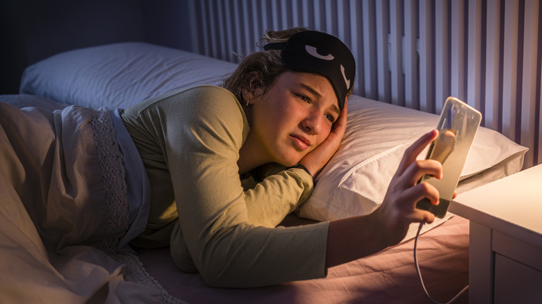 Teenage girl checking her smartphone at bedtime