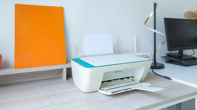 a workstation with printer, router and monitor placed on the desk