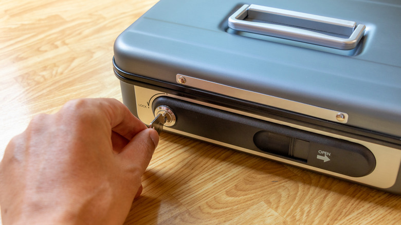 Someone using a key to open a valuables lockbox.