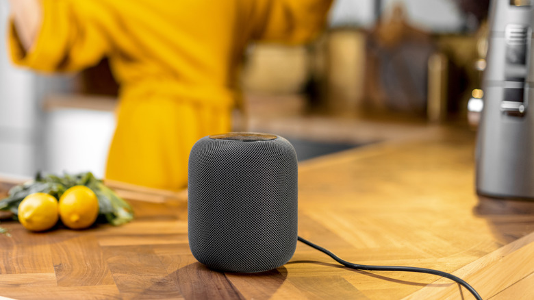 Smart speaker on a kitchen counter with cooking in the background.