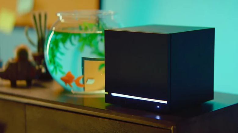 A black Steam Machine with an illuminated white strip and a power indicator sits next to a fish bowl containing a goldfish