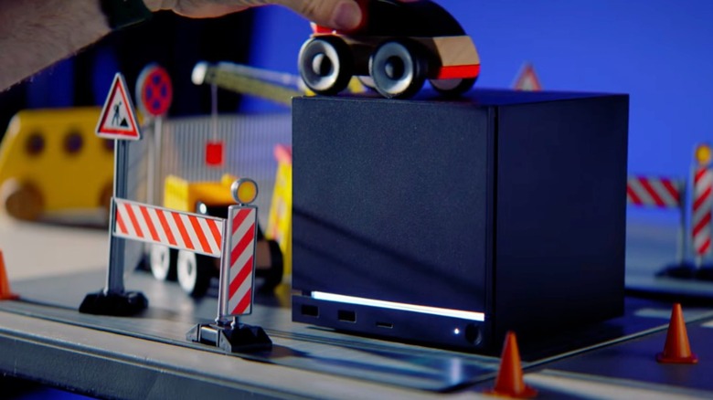 A black Steam Machine with an illuminated white light sits among model construction materials