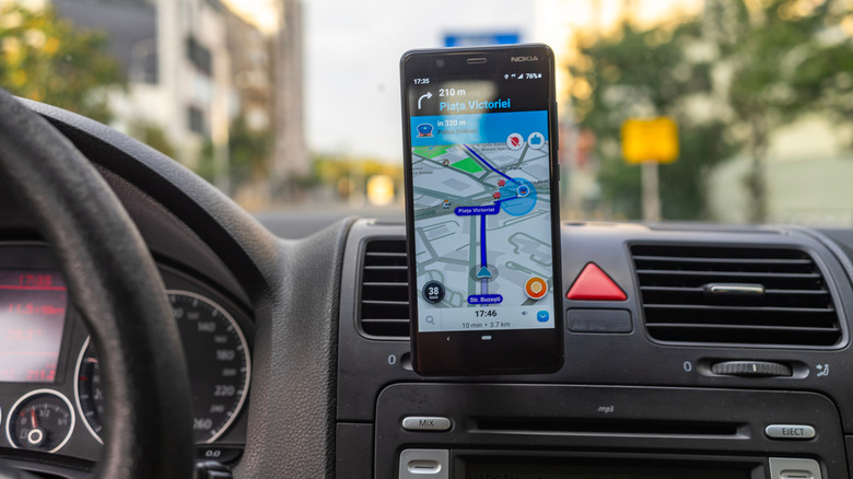 smartphone mounted inside a car in front of the AC vents running waze for navigation