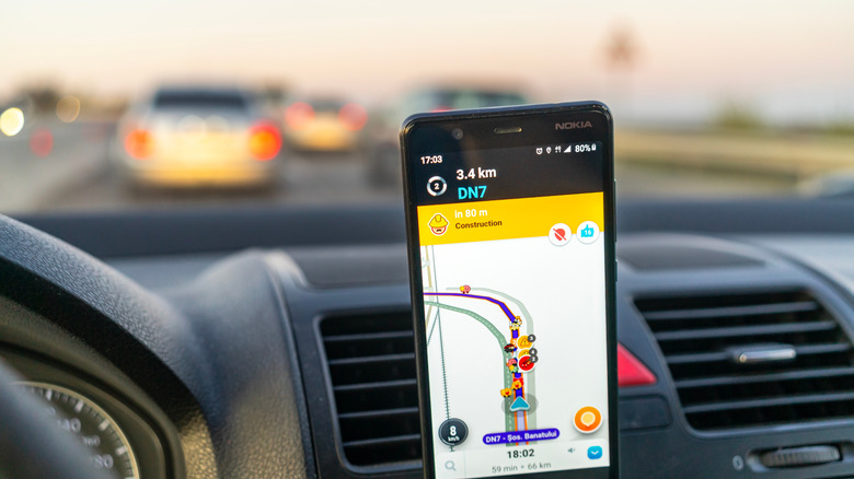 smartphone mounted inside a car showing directions along with alerts along the route