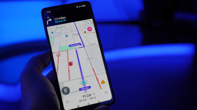 person holding a smartphone against a blue background running waze app for directions