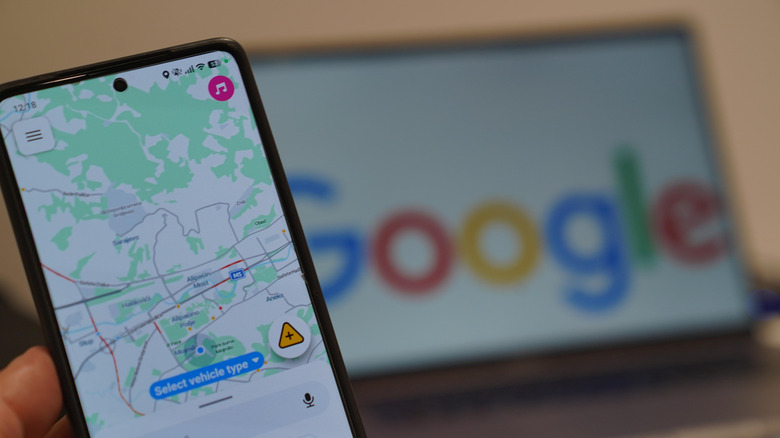 person holding a smartphone running the waze app with Google written on a screen in the background