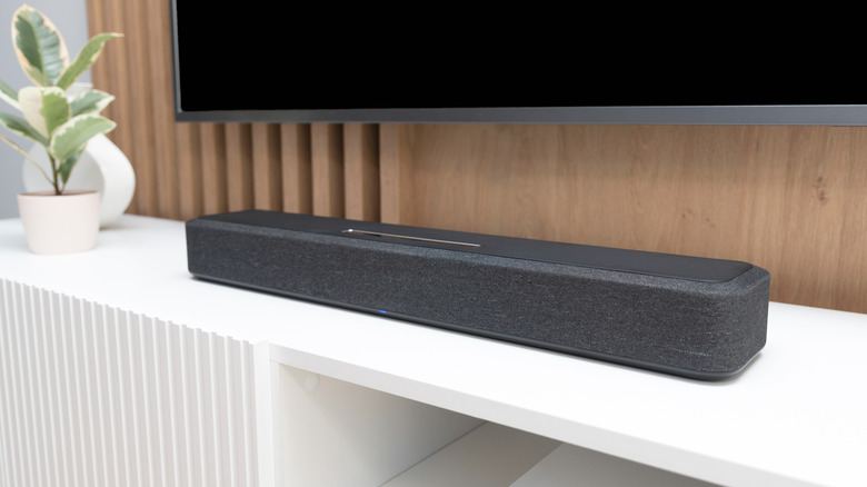 A compact soundbar set up below a wall-mounted TV in a modern living room.