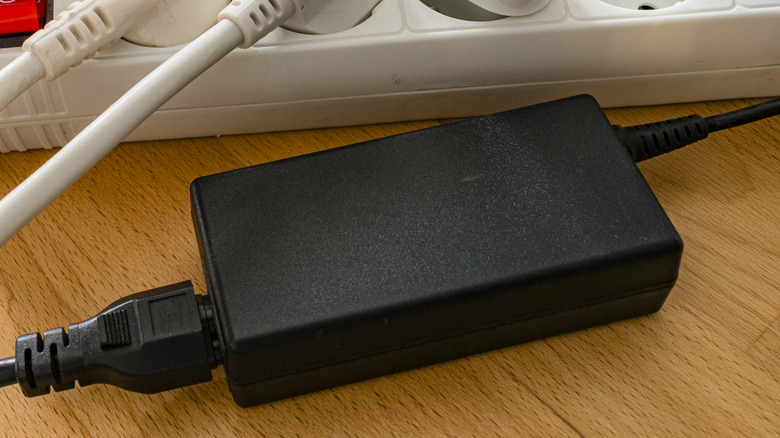 An AC power adapter next to a power strip.