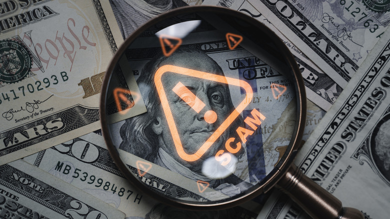 Magnifying glass focusing on scam warning symbol over dollar bills